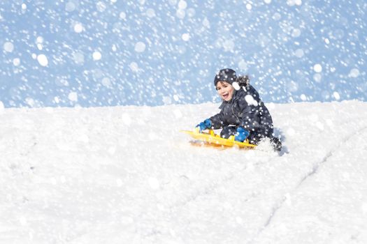 Boy on sleigh. Sledding during a snowfall on a winter day