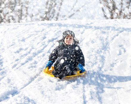 Boy on sleigh. Sledding during a snowfall on a winter day