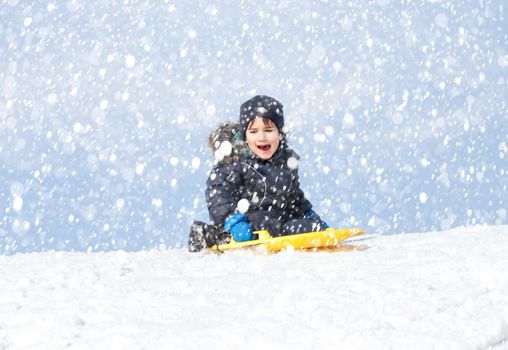 Boy on sleigh. Sledding during a snowfall on a winter day