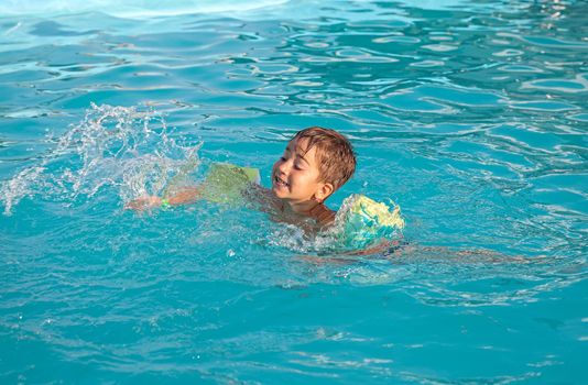 Little boy learning to swim in the pool 