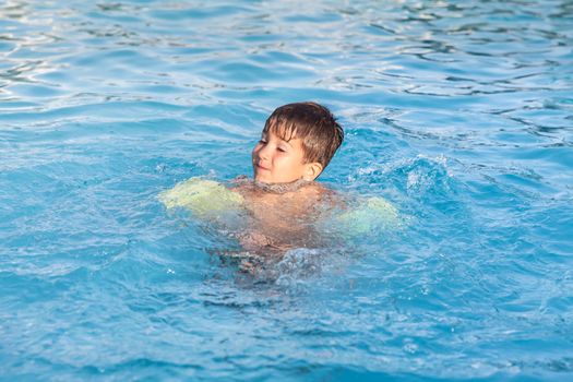 Little boy learning to swim in the pool 