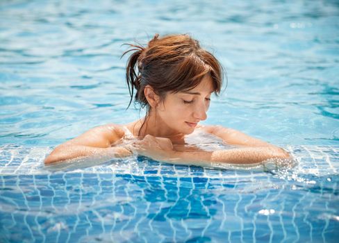 Portrait of a young woman with closed eyes relaxing in a swimming pool