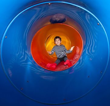 Cute young child boy playing in tunnel on playground