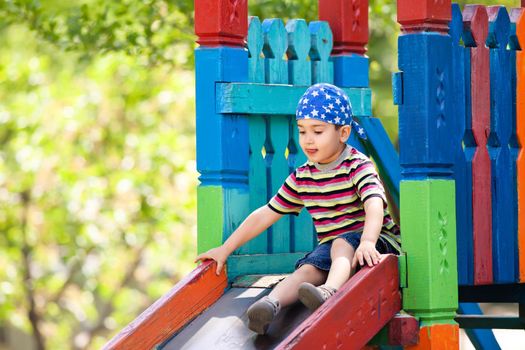 Cute boy in bandana playing on slide