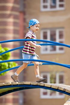 Young boy with toy gun walking on bridge at playground