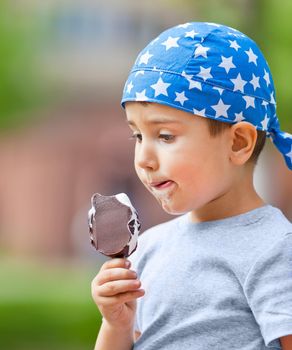 Cute little boy in bandana eats ice cream