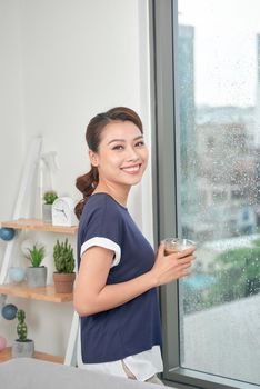 Attractive mixed female lifestyle enjoying a cup of tea looking out the window