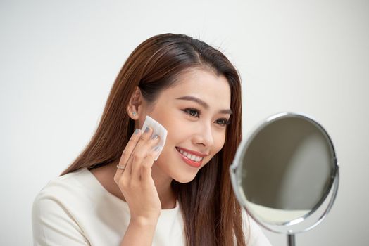 beautiful girl cleans the face of makeup with a cotton pad