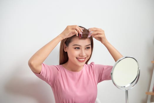 Beautiful woman with curlers smiling into mirror, enjoying her look, beauty