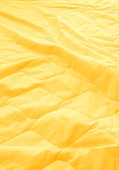 Yellow blanket crumpled on the bed