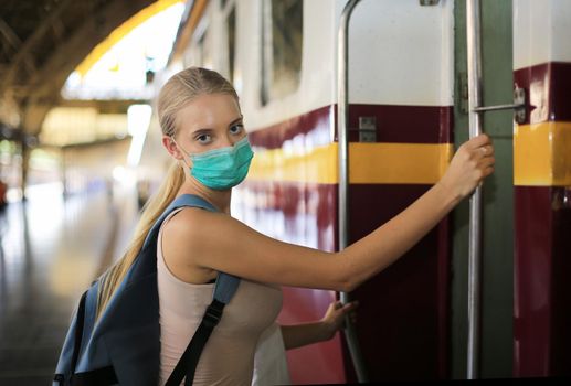 Portrait of confident young woman traveling by train, and wear protective face mask to prevent the spread of coronavirus, Covid-19