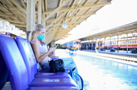 Portrait of confident young woman traveling by train, and wear protective face mask to prevent the spread of coronavirus, Covid-19