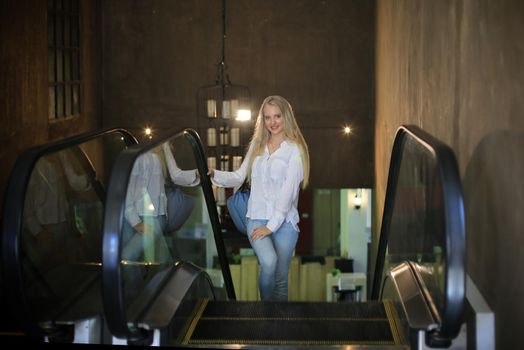 Beautiful blonde girl walking up the escalator.