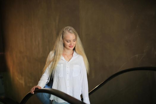 Beautiful blonde girl walking up the escalator.