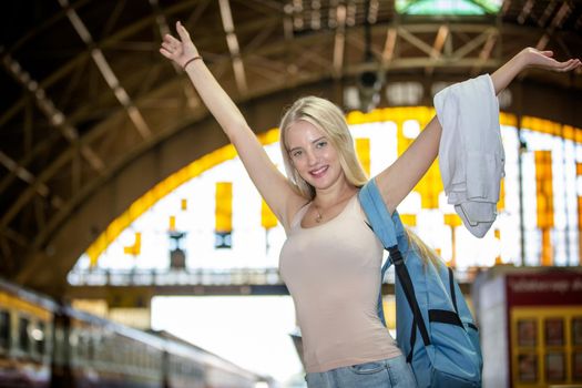 young woman waiting in vintage train, relaxed and carefree at the station platform in Bangkok, Thailand before catching a train. Travel photography. Lifestyle.