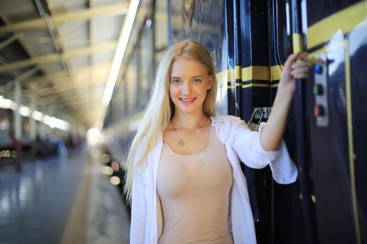 young woman waiting in vintage train, relaxed and carefree at the station platform in Bangkok, Thailand before catching a train. Travel photography. Lifestyle.