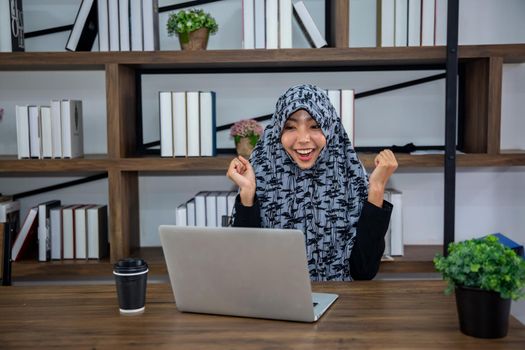 young Muslim woman using a laptop in a modern office