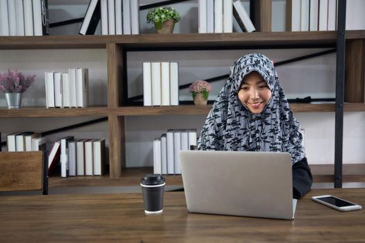 young Muslim woman using a laptop in a modern office