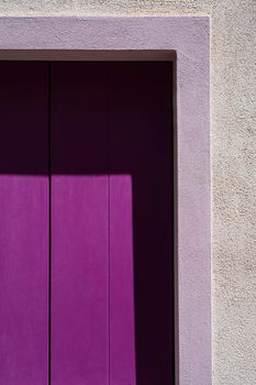 a wooden violet window on a house in the town center of Caorle, Italy