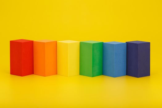 Flat lay with LGBT flag made of rectangular geometric figures on yellow background. Concept of Pride Month, human rights, LGBT community and tolerance. 