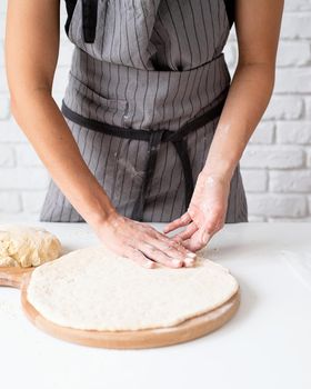 Home cooking. Woman kneading dough at home preparing pizza