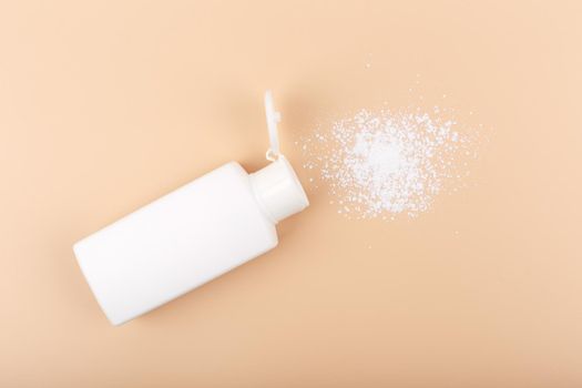 Top view of spilled hypoallergenic baby powder on light beige background. 