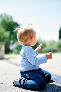 Little girl sits on her knees on the tile. Side view. High quality photo