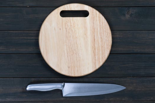 Close up kitchen knife and wooden round empty cutting board on a wooden table