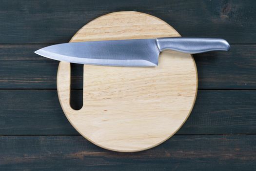 Close up kitchen knife and wooden round empty cutting board on a wooden table