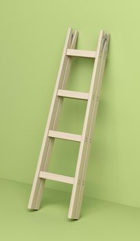 Wood double step ladder leaning against the green wall