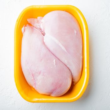 Fresh chicken breast meat in open tray, on white background