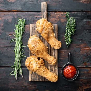 Crispy fried chicken cuts on old dark wooden table, top view.