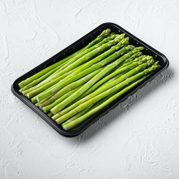 Asparagus. Fresh Asparagus. Pickled Green Asparagus set, in plastic market container, on white stone background, square format