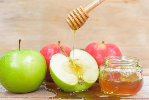 Jewish holiday, Apple Rosh Hashanah, the photo have honey in jar and drop honey on green apples on wooden background