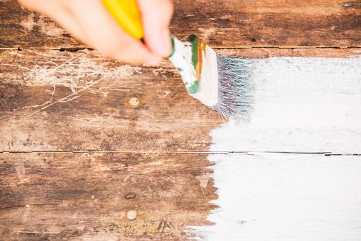 DIY, closeup Woman hand using paintbrush decorating or painting old wood brown color to white color on the wooden board table