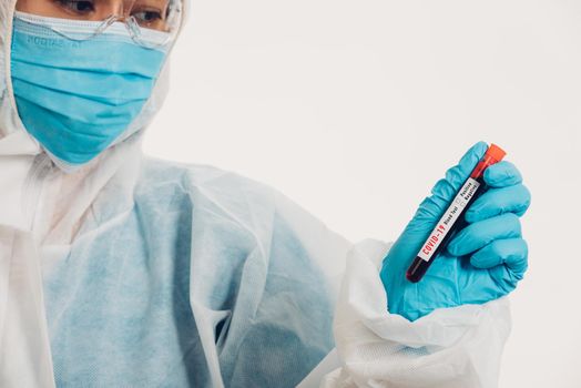 Medical scientist in PPE uniform wear a mask holding test tube Coronavirus test blood sample in a hospital laboratory for analyzing isolated on white, medicine COVID-19 pandemic outbreak concept