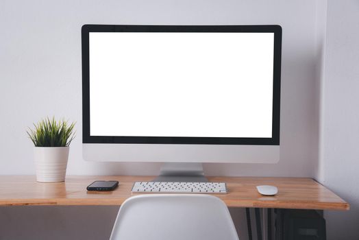 Computer monitor with white blank screen on the business desk with wireless mouse, keyboard at home office over white wall background, Photo of equipment contemporary workspace