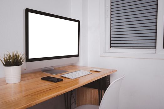 Computer monitor with white blank screen on the business desk with wireless mouse, keyboard at home office over white wall background, Photo of equipment contemporary workspace