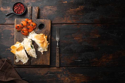 Chicken kiev filo set, with baked cherry tomatoes, on serving board, on old dark wooden table background, top view flat lay, with copy space for text