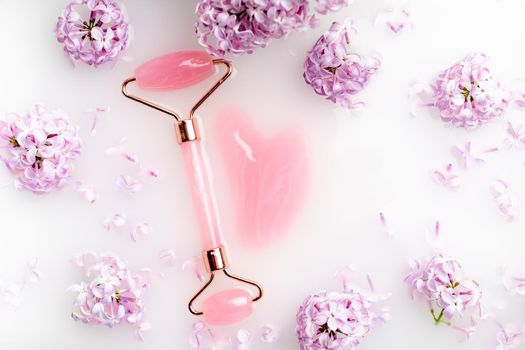 Roller facial massager and lilac in milk . Facial care. Skin care. Cosmetology. Massage. Lilac bush. Copy space