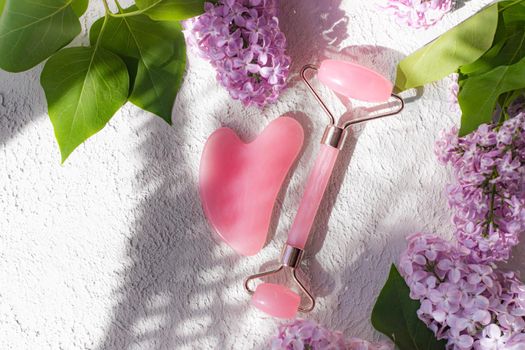 Roller face massager and lilac on a white background . Facial care. Skin care. Cosmetology. Massage. Lilac bush. Copy space