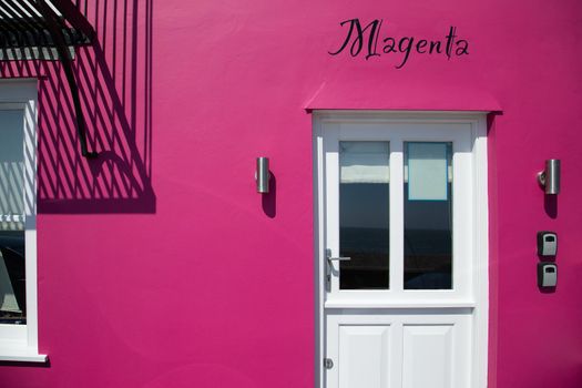 Magenta coloured old house. Front view. Colourful old UK house facade with text Magenta on it.