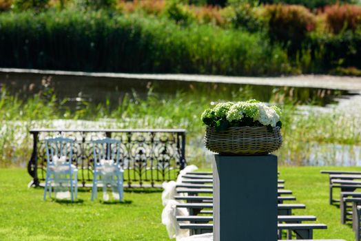 hortensia flowers as wedding decoration in a garden with a lake in the background and white chairs and grey banks wating for people.