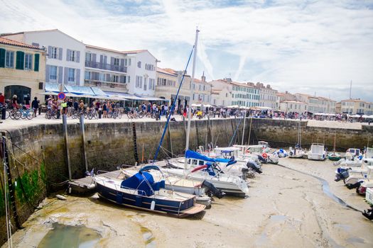 View on the harbor of Saint-Martin-de-Ré at lowtide with boats and people walking on a sunny summerday