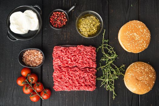 Fresh raw minced beef meat for meatball burgers with sesame buns set, on black wooden table background, top view flat lay