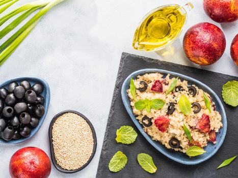 Salad with quinoa, red orange, black olives, green onion, mint and olive oil on gray concrete backkground. Vegan food. Top view or flat lay. Copy space.