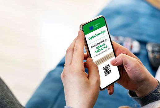 woman holding a smartphone with Covid-19 digital certificate on the screen. Digital Green Pass allows traveling within the European Union without the travel restrictions due to the Covid-19 pandemic