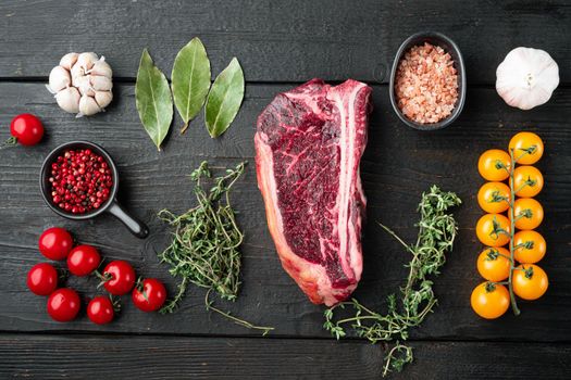 Raw fresh marbled meat black angus club steak and ingredients set on black wooden table background, top view flat lay