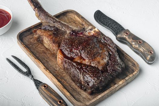 Tomahawk beef steak Grilled with spices set, on wooden serving board, on white stone background