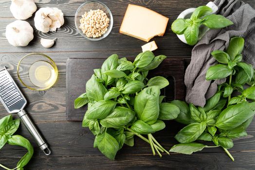 Pesto Sauce. Italian Cuisine. Step by step cooking italian pesto sauce. Step 1 - preparing all ingredients. Fresh green basil, parmesan cheese, nuts, olive oil and garlic top view on black wooden table